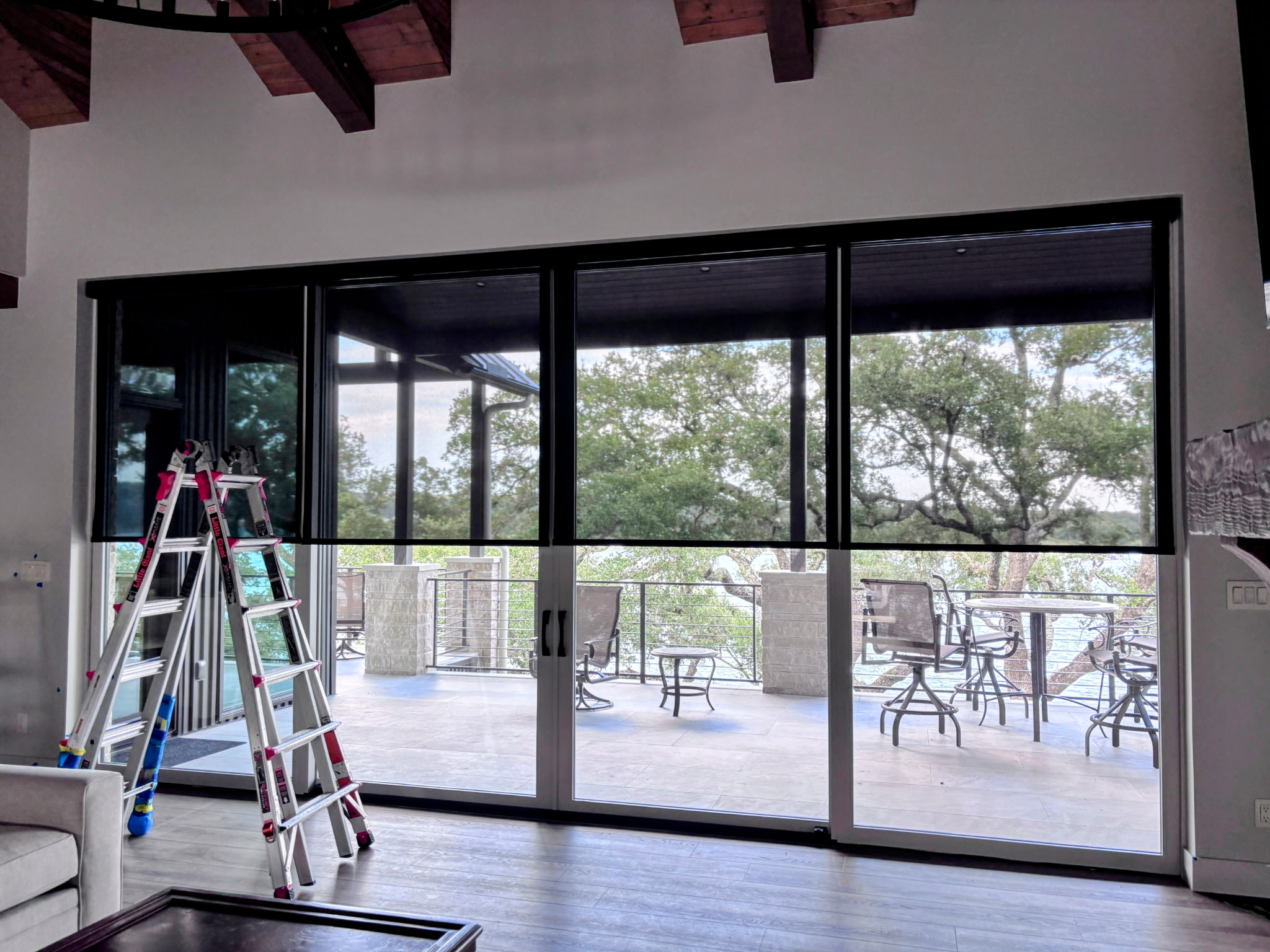 Dark roller shades across wide glass patio doors